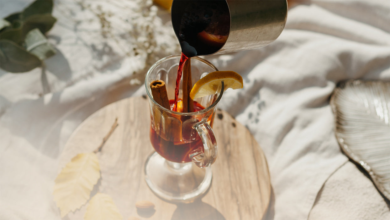 Glas Kombucha Orangen Punsch Kanne giesst ein Zimtstange Holzbrett Tuch