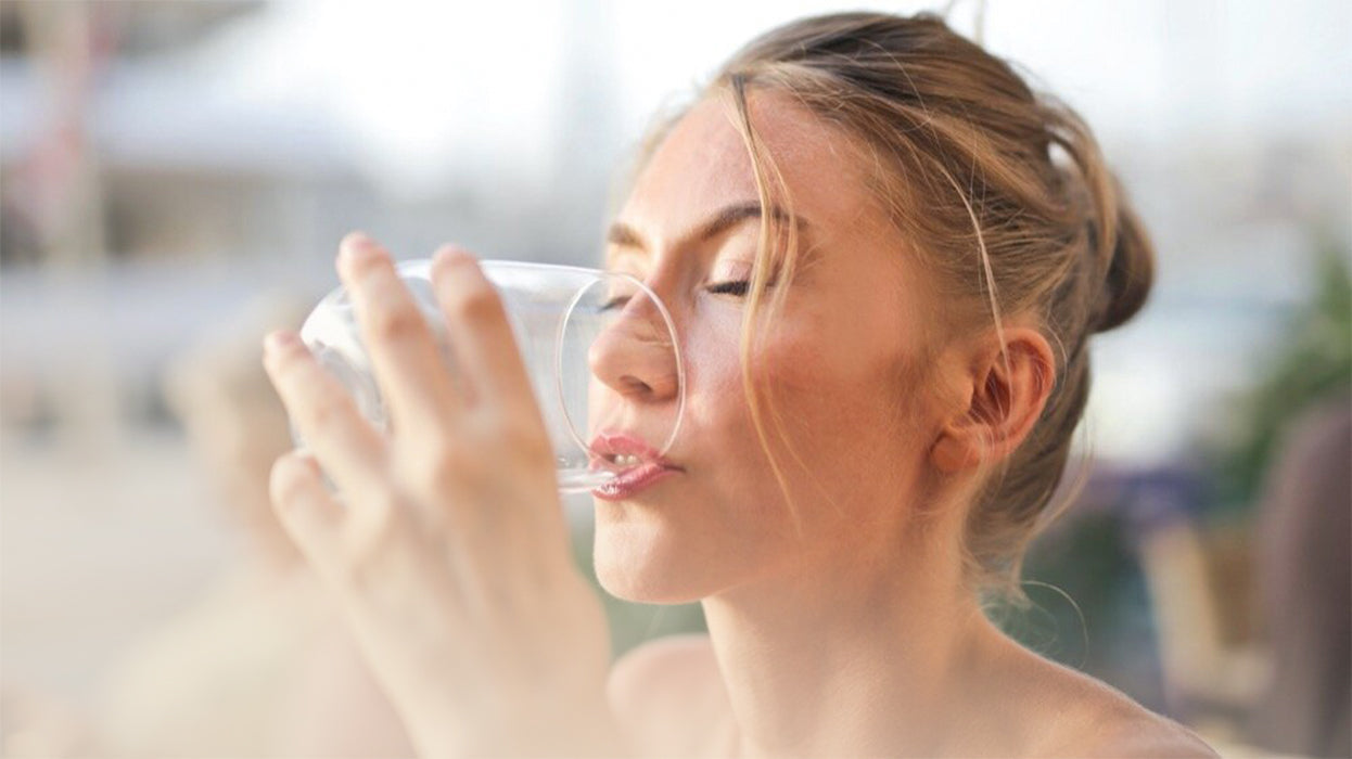 Frau trinkt Wasser aus Glas